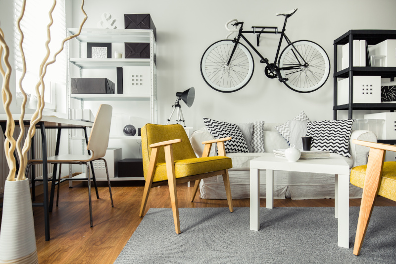 Einzimmerwohnung mit gelben Stühlen und weißer Couch und Fahrrad an der Wand