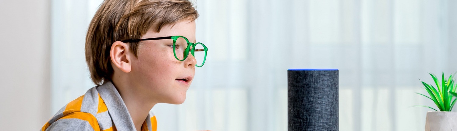 Voice controlled smart speaker. Little kid girl talking to talking to Amazon Alexa Echo Dot. Education programme for child. Boy talking to Alexa and give it orders and commands what to switch on. Kleiner Junge steht vor Amazon Echo Lautsprecher